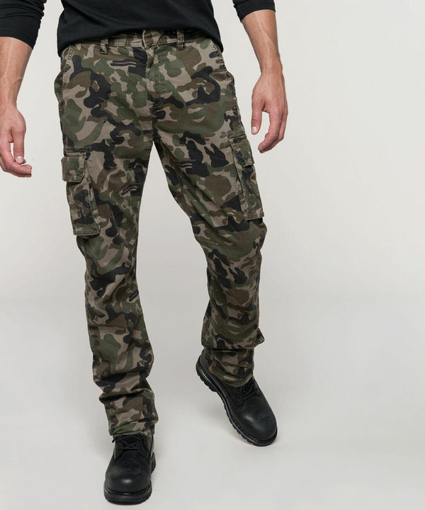 A person wearing Kariban KB744 camouflage cargo pants and black boots, showing only the lower half of the body against a plain background.