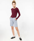 A woman wearing a maroon long-sleeve shirt, light gray shorts, white socks, and black boat shoes stands with her hands in her pockets against a plain white background, showcasing the KB753 by Kariban.
