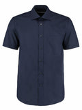 The product KK102 by Kustom Kit is a navy blue short-sleeve button-up shirt featuring a chest pocket.