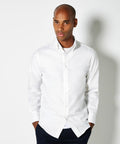 A person wearing a Kustom Kit KK188 white button-up shirt with hands in pockets, standing against a plain white background.