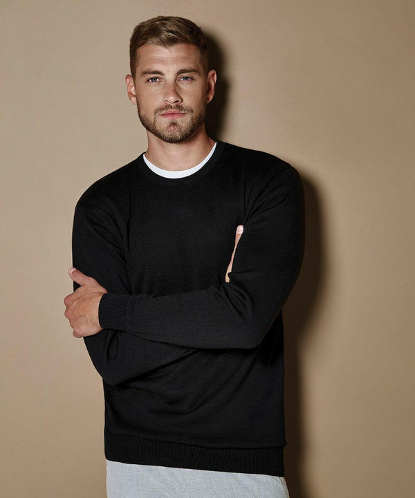 A man with short hair and a beard stands against a beige background, wearing the KK253 Kustom Kit sweater over a white shirt, with his arms crossed.