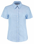 The product is a Kustom Kit KK360, featuring a light blue design with short sleeves and a classic collar, showcased against a white background.