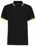 Kustom Kit's KK409 is a black polo shirt featuring yellow stripe details on the collar and sleeves.