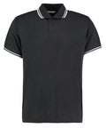 The KK409 by Kustom Kit is a black polo shirt featuring a button-up collar with white stripes along the edges of the collar and sleeves.