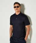 A man wearing dark sunglasses and a Kustom Kit KK455 navy polo shirt stands against a plain background.