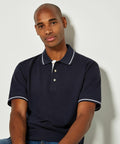 A person wearing a dark KK606 polo shirt with white trim from Kustom Kit sits against a plain background.