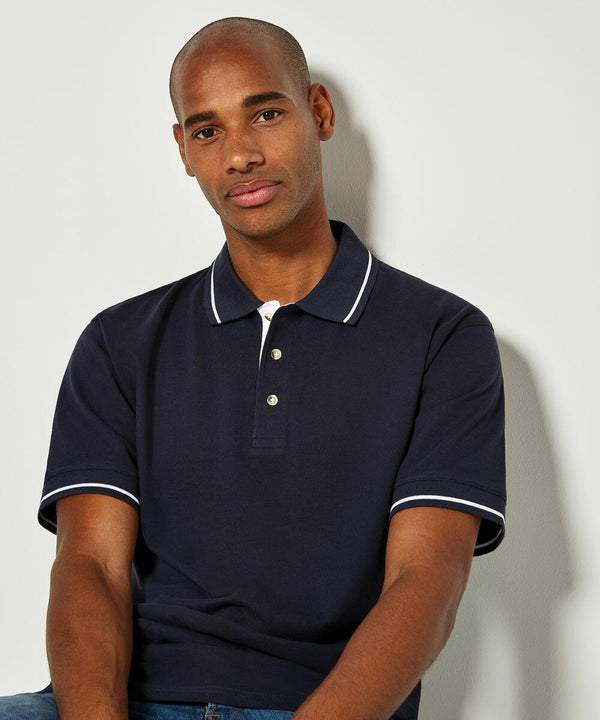 A person wearing a dark KK606 polo shirt with white trim from Kustom Kit sits against a plain background.