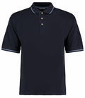 The Kustom Kit KK606 is a navy blue polo shirt featuring short sleeves and a three-button placket, with subtle white stripe detailing on the collar and sleeve cuffs.