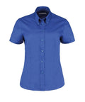 The KK701 by Kustom Kit is a neatly pressed, short-sleeved, button-up shirt featuring a classic pointed collar in blue, elegantly displayed against a plain white background.
