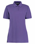 The KK703 by Kustom Kit is a plain purple polo shirt featuring short sleeves and a classic collar, with three buttons on the front placket. The shirt is displayed against a white background.