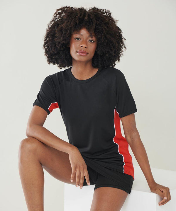 A person with curly hair wearing a black and red Finden & Hales LV240 sports outfit sits with one leg bent and the other extended, posing for the camera.