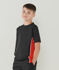 A boy wearing a black Finden & Hales LV242 t-shirt with red and white side panels stands against a neutral background with his hands in his pockets.