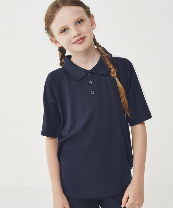 A young girl with light skin and brown plaited hair stands against a plain background, wearing the Finden & Hales Kids team polo shirt in navy blue. She looks at the camera with a slight smile.
