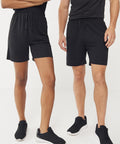 Two people stand side by side against a plain white background, both wearing black Finden & Hales Adults team shorts with no pockets, matching black shirts, and black trainers. Their heads are not visible in the image.