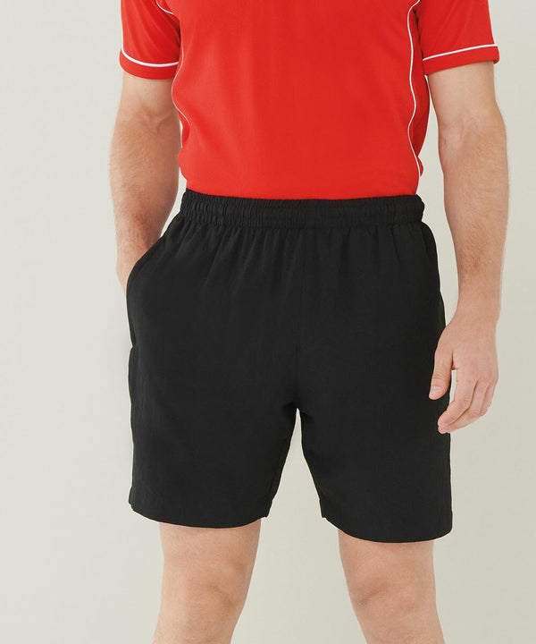 A person wearing a Finden & Hales LV830 red shirt and black shorts with hands in pockets is shown from the shoulders down against a light-colored background.