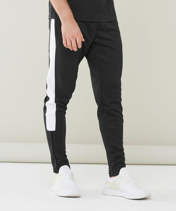 Man wearing black Finden & Hales LV881 athletic track pants with white side stripes and white athletic shoes against a plain background.