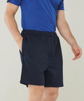 Person wearing a blue Finden & Hales LV886 shirt and dark blue shorts standing with one hand in their pocket.