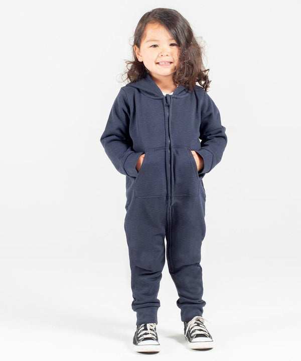 A young child with long hair stands smiling, hands in pockets, wearing a navy blue hooded jumpsuit and black Larkwood LW70T sneakers.