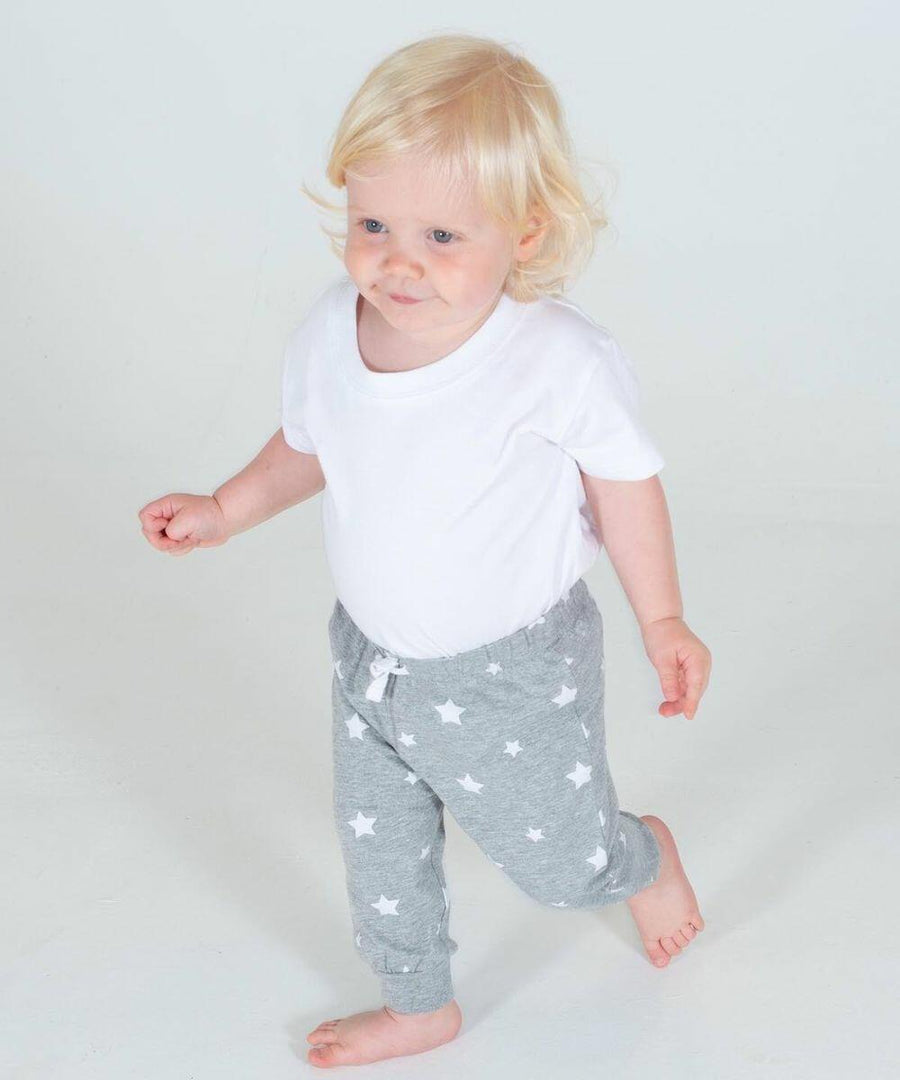 A toddler with blond hair wearing a white LW85T Larkwood shirt and gray star-patterned pants walks barefoot on a white background.