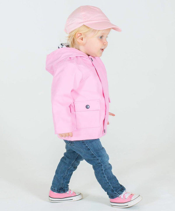 A young child wearing a pink hat, a pink Larkwood LW90T jacket, blue jeans, and pink sneakers walks against a plain white background.