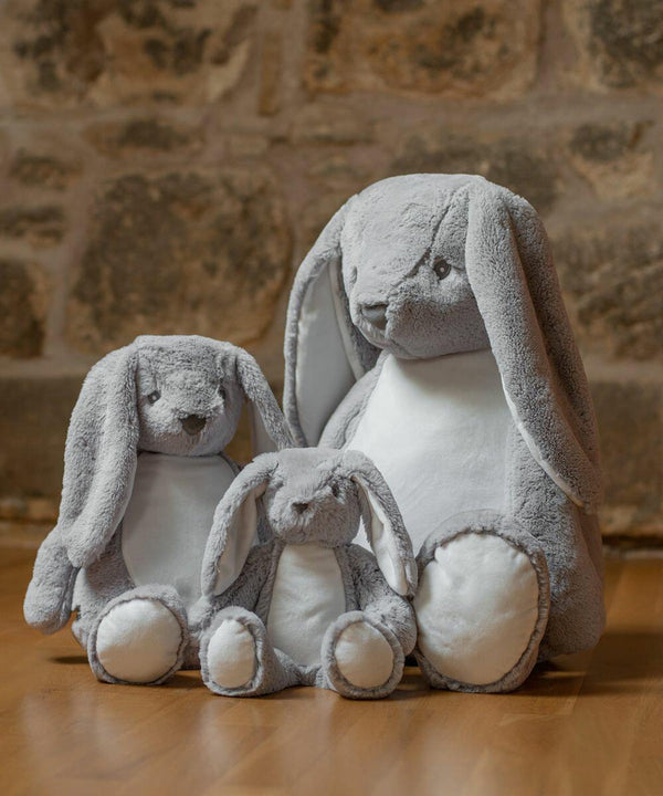 Three Mumbles MM050 of varying sizes, each with gray fur and white bellies, sit on a wooden floor against a stone wall background.