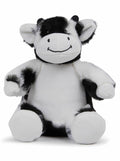 The MM060 from Mumbles is a plush toy styled as a smiling cow, featuring black and white patterned fur. It sits upright with its arms slightly outstretched.