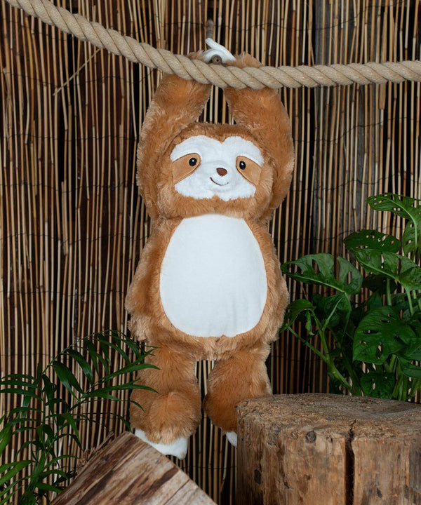 A Mumbles MM572 hangs by its arms from a thick rope in front of a bamboo backdrop, with green plants and wooden blocks surrounding it.