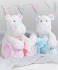 Two stuffed hippo toys holding rolled blankets, one with a pink blanket and bow and the other with a blue blanket and bow, against a backdrop with bunting. The product is the Mumbles MM606.