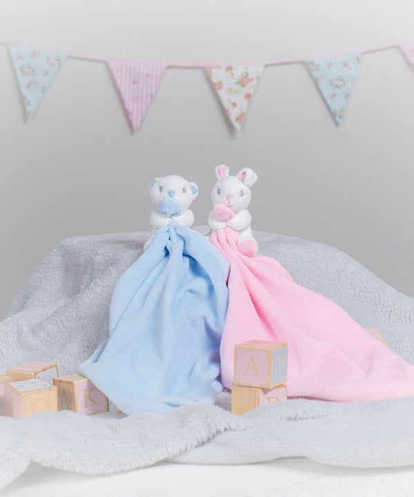 Two Mumbles MM700 stuffed animals holding blankets, one blue and one pink, sit on a gray blanket. Colorful, triangular bunting is hung in the background. Wooden blocks with letters are placed around them.
