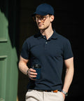 Man in a dark polo shirt and cap holds a Nimbus NB37M while standing outdoors.