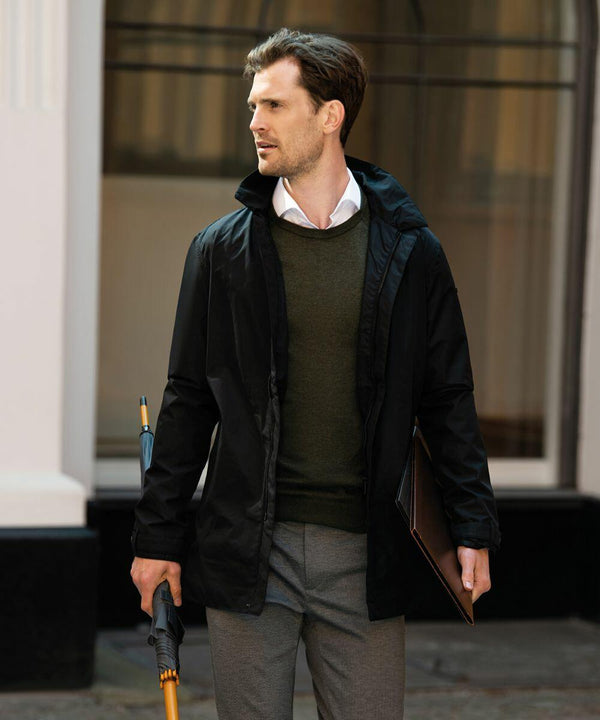 A man wearing a black jacket and grey pants holds a Nimbus NB51M and a folder while standing outside a building.