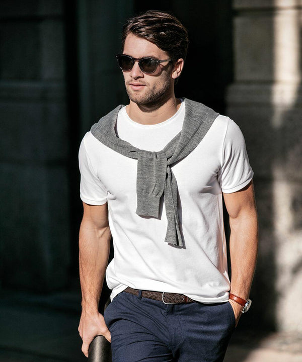 A man wearing Nimbus NB72M sunglasses, a white T-shirt, and a gray sweater draped over his shoulders stands outdoors.