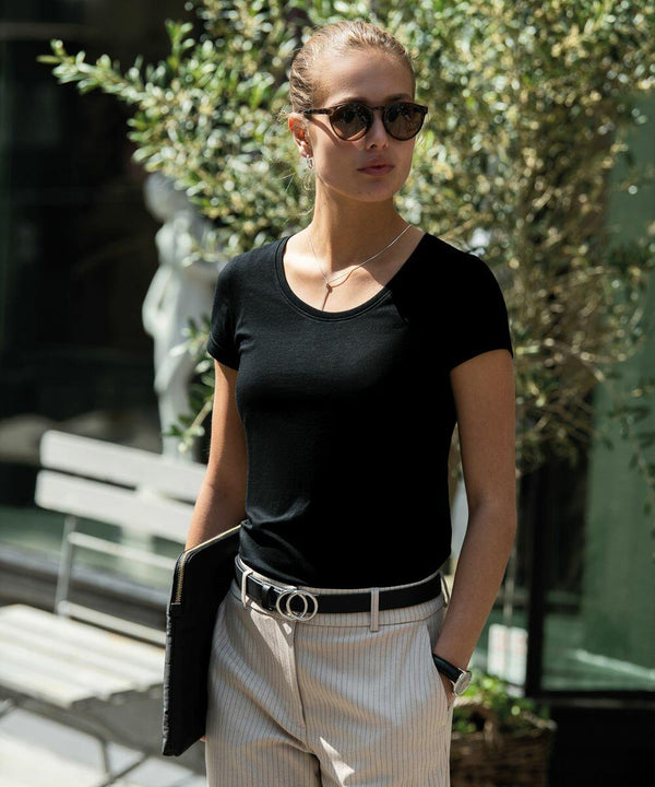 Person in sunglasses and a black shirt stands outdoors, holding a Nimbus NB73F laptop against a backdrop of greenery and a bench.
