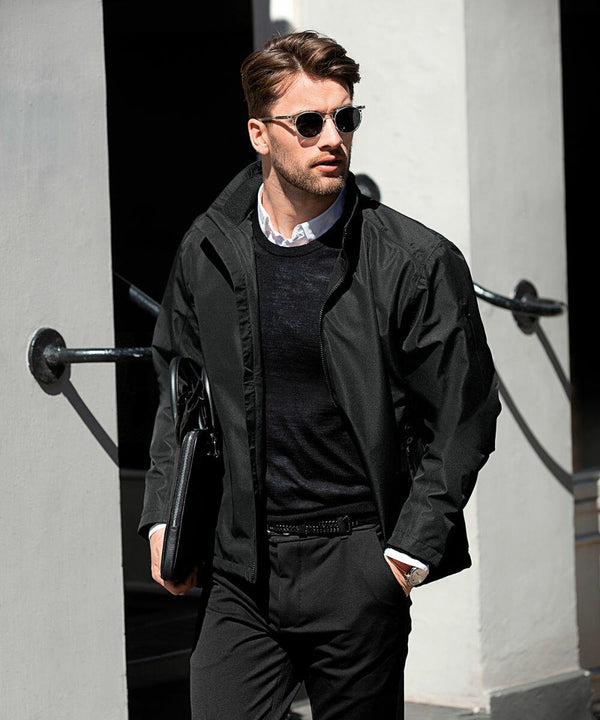 A man wearing sunglasses and a black jacket over a dark sweater and white shirt, holds a Nimbus NB97M while walking.