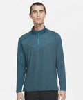 A person stands facing forward wearing a teal NK339 quarter-zip pullover by Nike and black pants against a plain white background.
