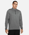 A man stands facing forward, wearing a gray Nike NK355 quarter-zip pullover and black pants, against a plain white background.
