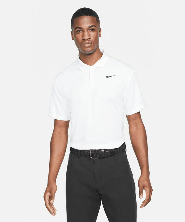 A man in a white polo shirt with an NK372 Nike logo and black pants stands facing the camera.