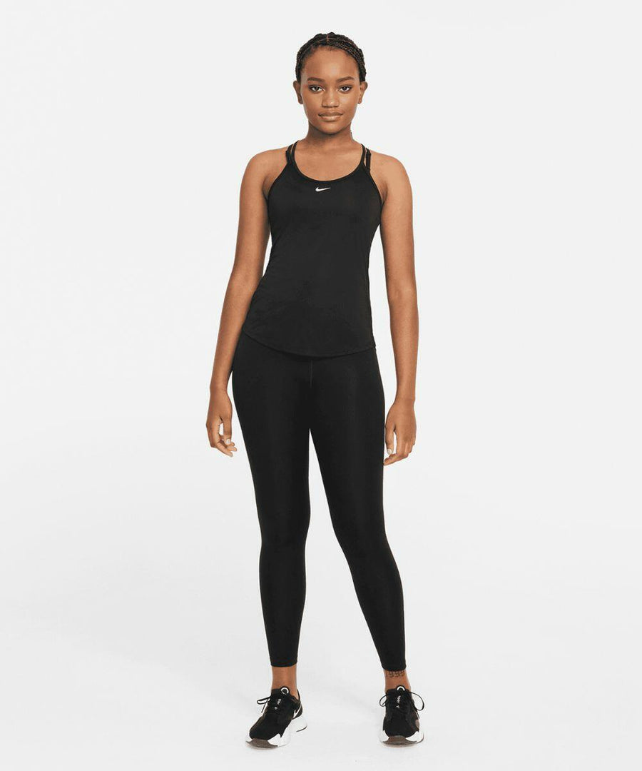 A person stands facing forward, wearing a black Nike NK375 athletic tank top, black leggings, and black sneakers. The background is plain white.