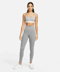 A person stands facing forward wearing a gray Nike NK376 sports bra, high-waisted gray leggings, and white athletic shoes against a plain white background.
