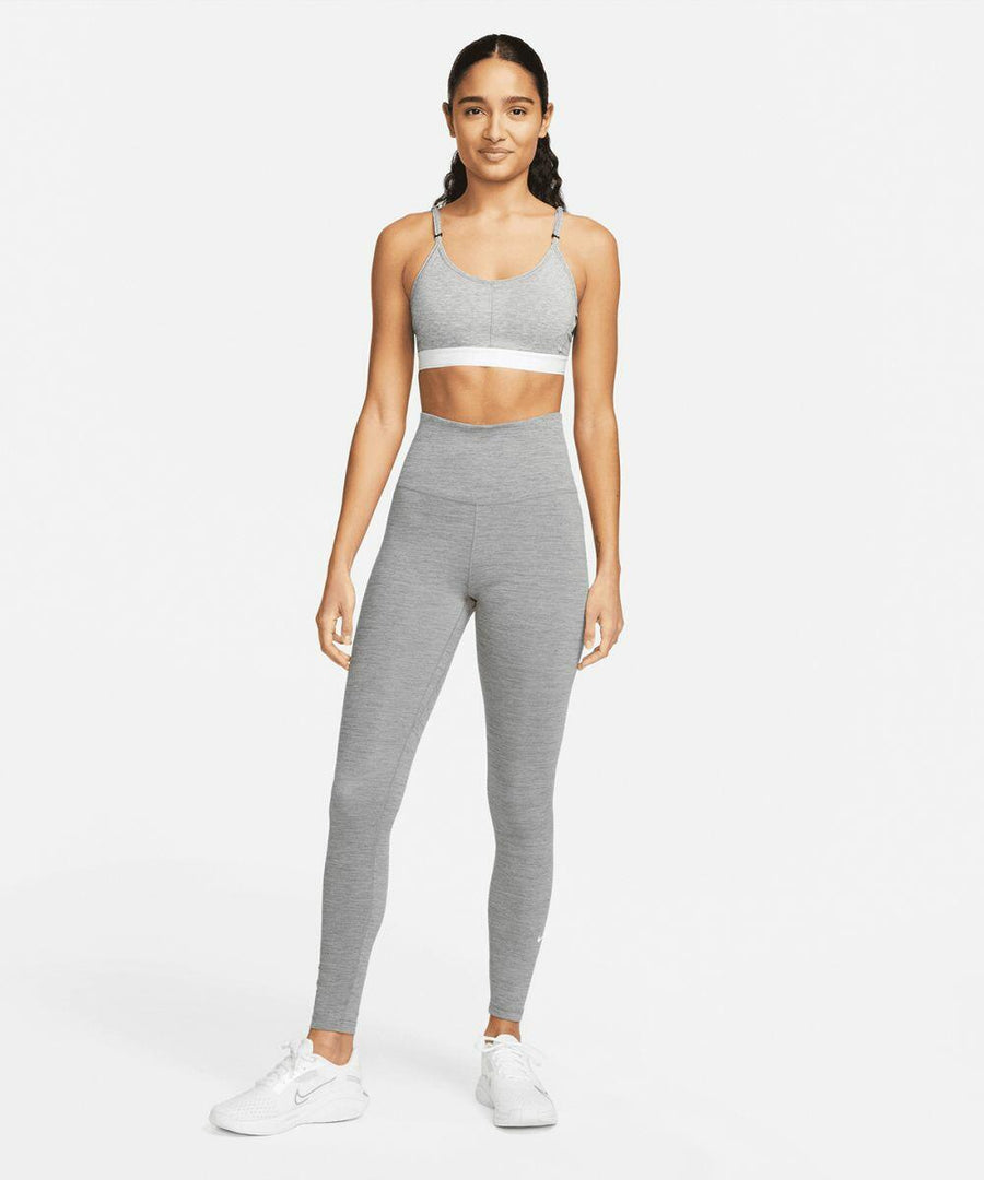 A person stands facing forward wearing a gray Nike NK376 sports bra, high-waisted gray leggings, and white athletic shoes against a plain white background.
