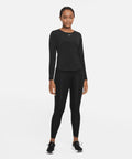Person dressed in black athletic wear, including a long-sleeve Nike NK378 shirt, leggings, and sneakers, standing against a plain white background.