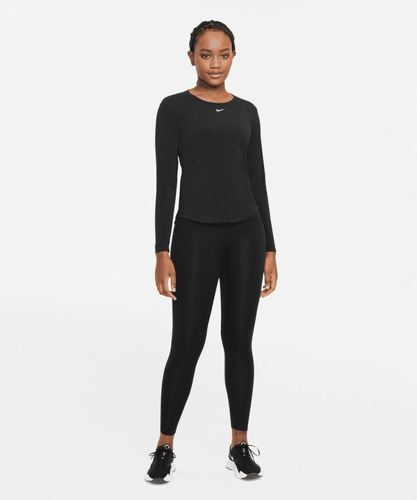 Person dressed in black athletic wear, including a long-sleeve Nike NK378 shirt, leggings, and sneakers, standing against a plain white background.