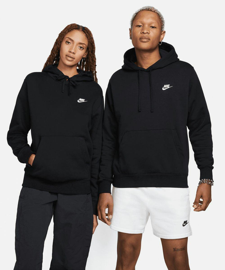 Two individuals stand side-by-side, both wearing black Nike NK387 hoodies. The person on the left wears dark pants, and the person on the right wears white shorts.