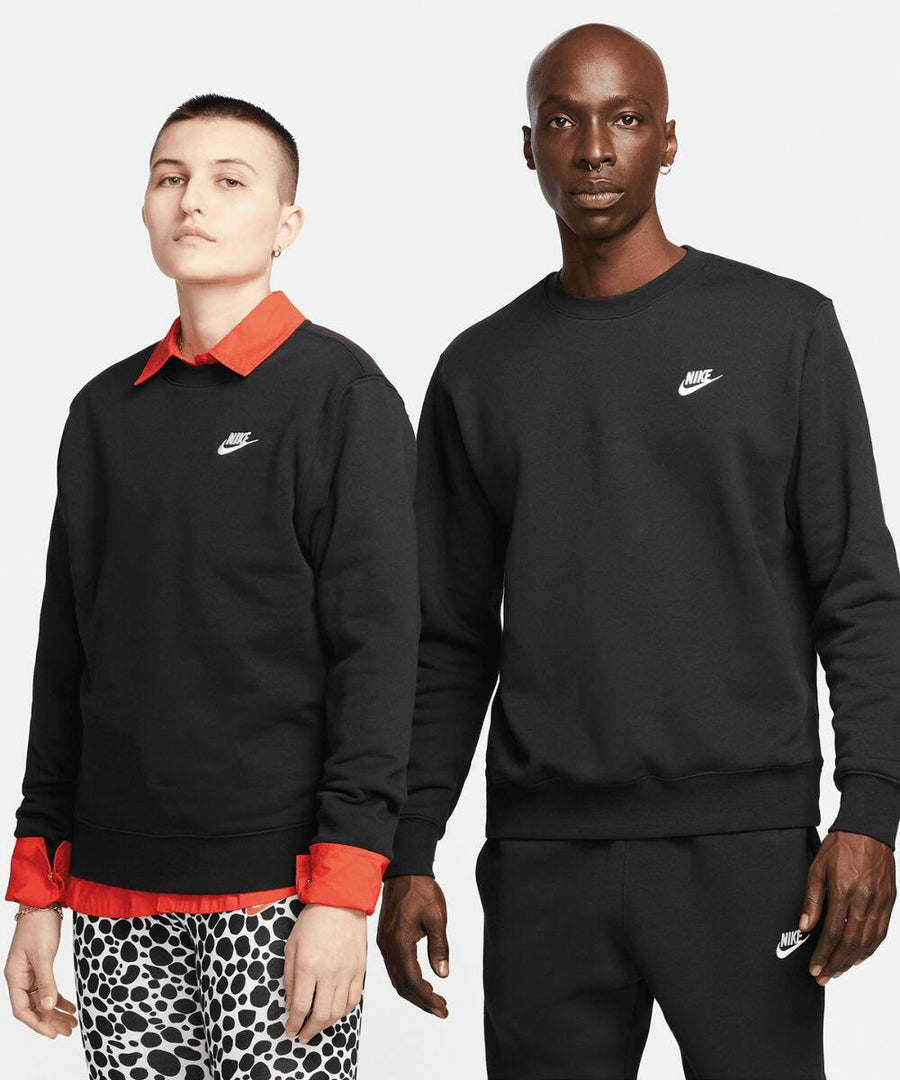 Two people wearing black Nike NK388 sweatshirts. The individual on the left has short hair and is paired with a red shirt and spotted pants. The person on the right has a bald head and is wearing matching black pants.
