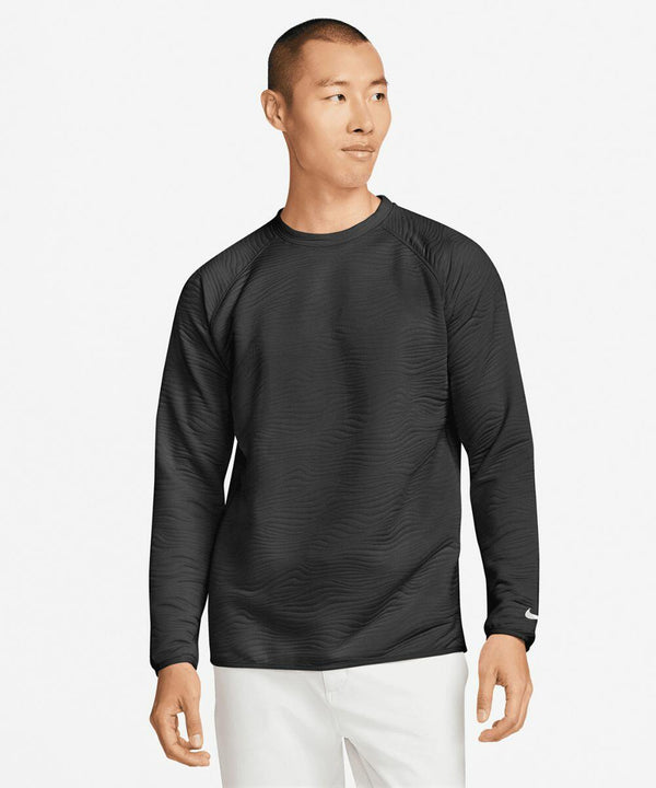 A man in a black Nike NK394 long-sleeved shirt stands against a plain white background. He is looking to the side with a neutral expression.