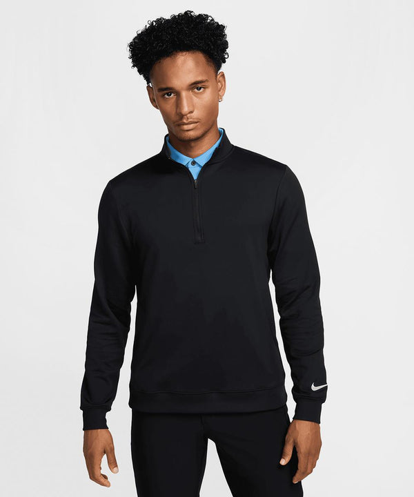 A person faces the camera wearing a Nike Tour half-zip top in black over a blue collared shirt, with a neutral expression, against a plain white background.