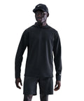 A person wearing a black Nike Velocity hoodie, black shorts, and a black cap featuring a white Nike logo stands against a plain white background.