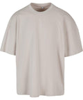 A light beige oversized T-shirt with short sleeves, a crew neckline, and relaxed fit is displayed against a white background.