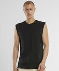 A person with short hair wears the New Morning Studios sleeveless tee, paired with beige trousers, facing the camera against a plain light background.