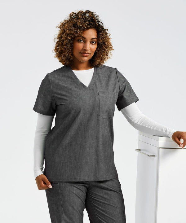 A person wearing gray medical scrubs and a white long-sleeve shirt stands next to a white NN300 by Onna with a neutral expression.
